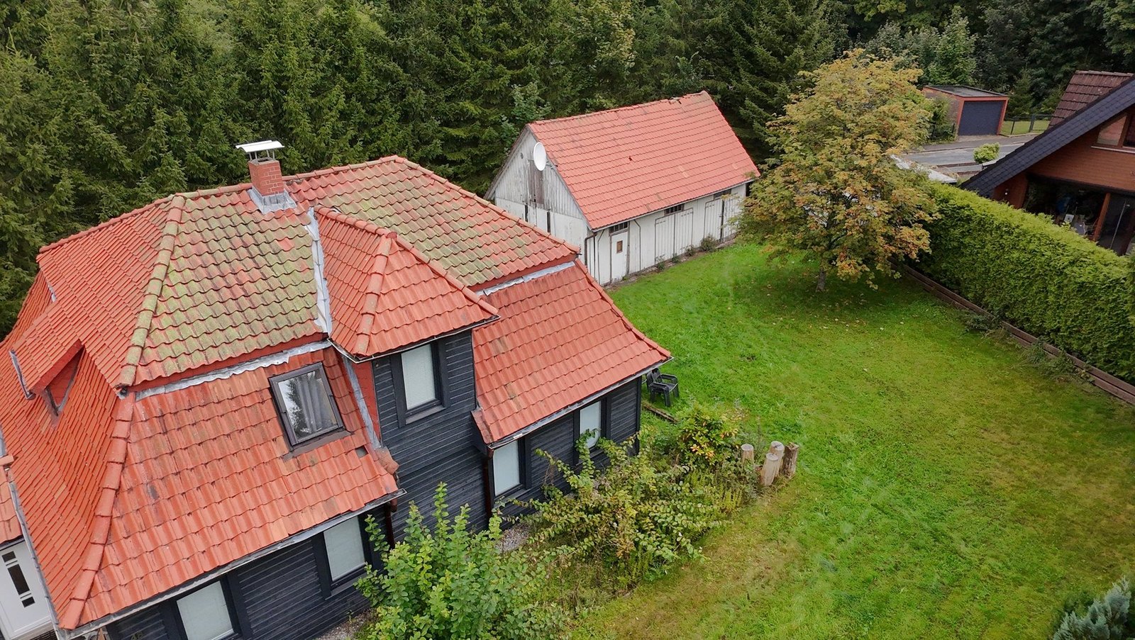 Luftaufnahme des Ferienhauses mit großem Grundstück und angrenzendem Wald.