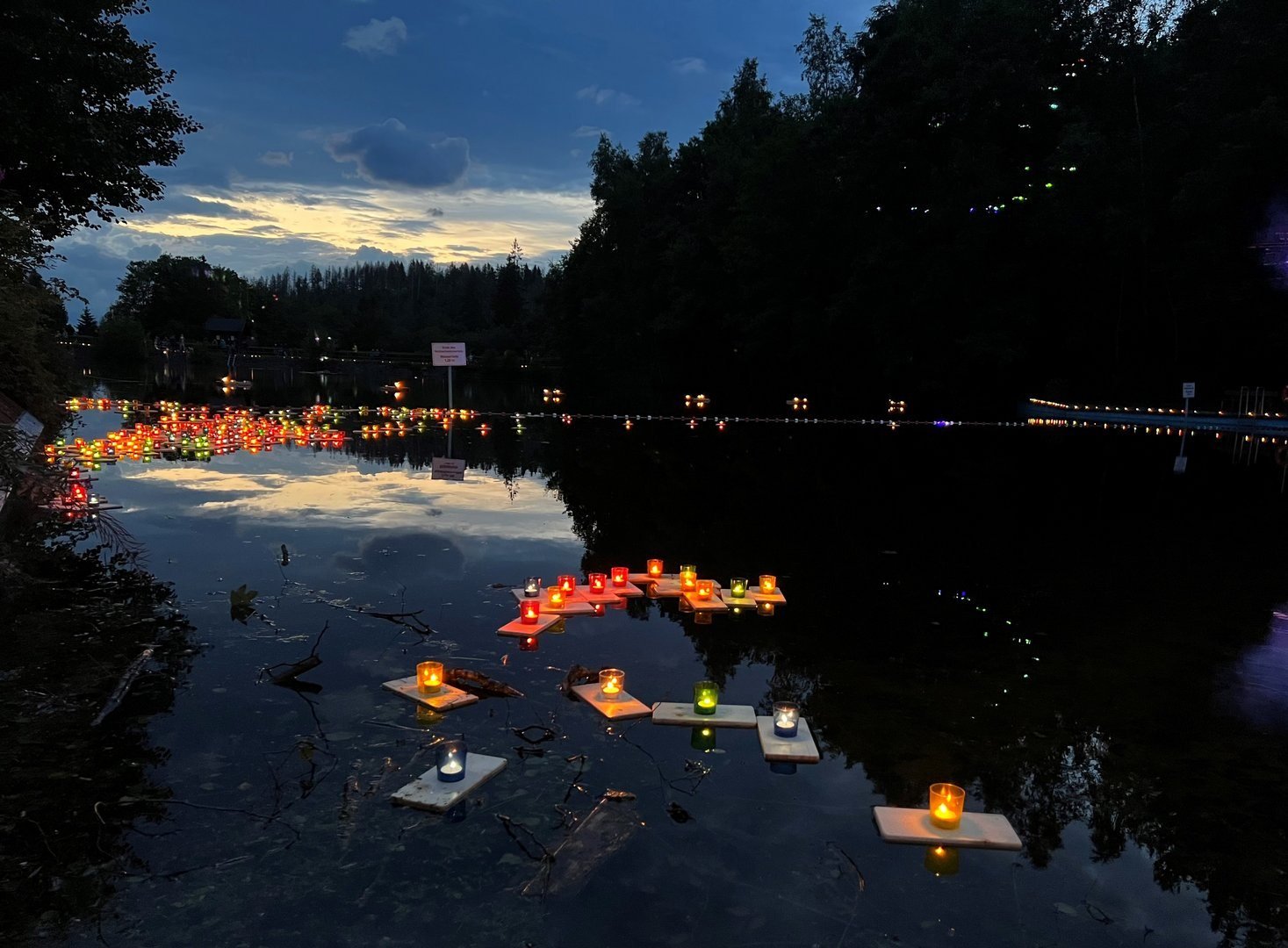 Schwimmende Lichter und Kerzen auf dem Okerteich beim Lichterfest in Altenau in der Abenddämmerung.